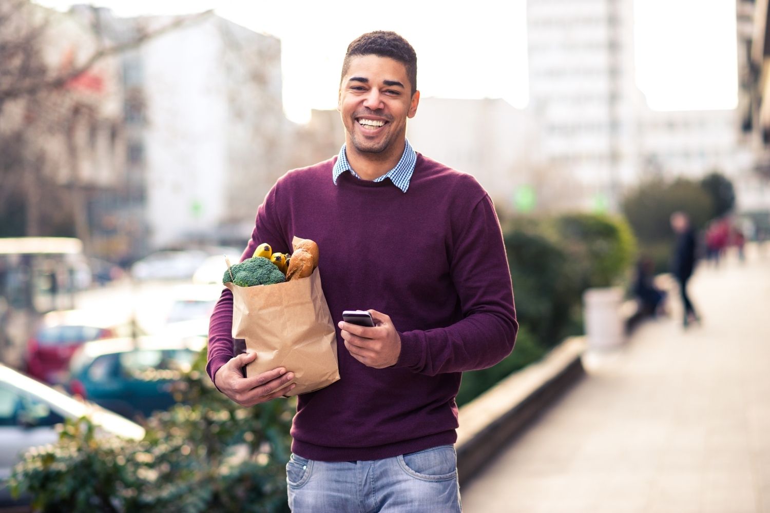 A man smiling and holding a basket of fresh fruits and vegetables
